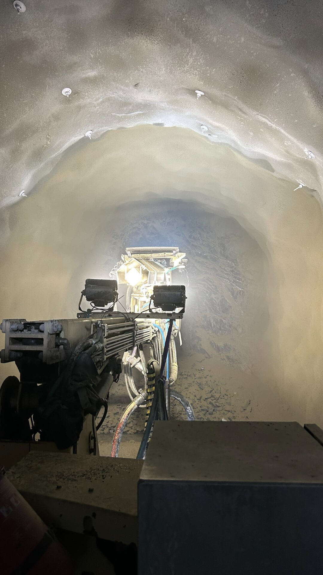 Tunnelboremaskin i aksjon under fjellsikringsarbeid i tunnel.
